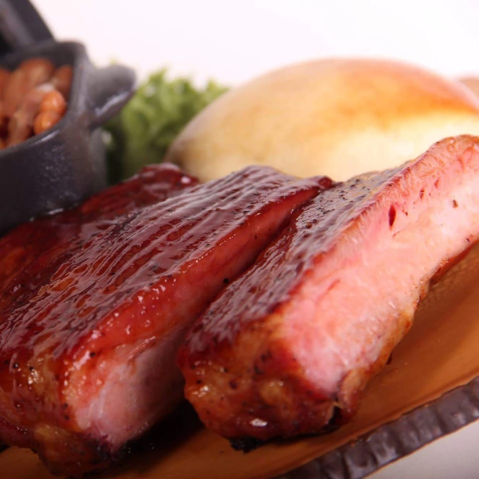 Holy Smokes BBQ ribs with a glossy sauce, baked beans, and a bun.