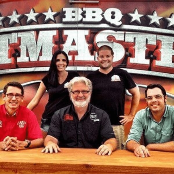 Five smiling people, three men and two women, posing in front of a "BBQ Master" sign.