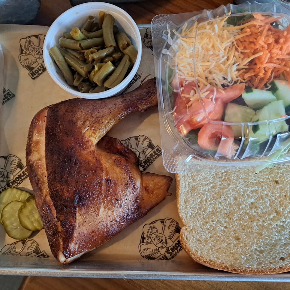 Holy Smokes BBQ chicken quarter with green beans, side salad, pickles, and white bread.