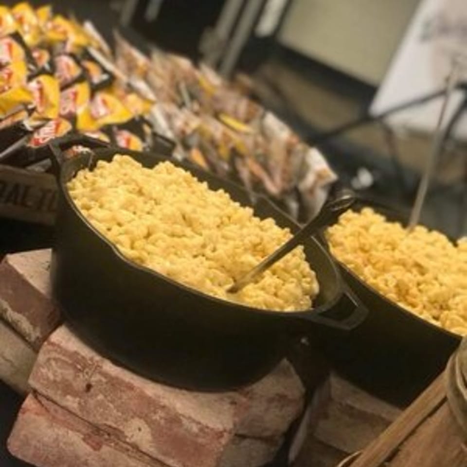 Holy Smokes BBQ's creamy mac and cheese in a black cast iron pot, with bags of chips in the background.